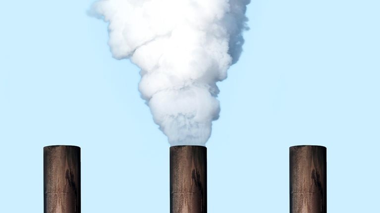 Five smoke stakes line up against a backdrop of a blue sky. A thick cloud of white smoke pours out from one of the stakes.