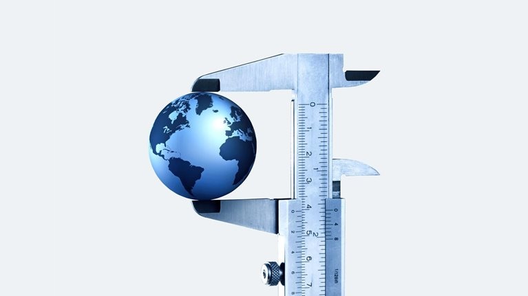 A globe in a vernier caliper set against a light gray background. 