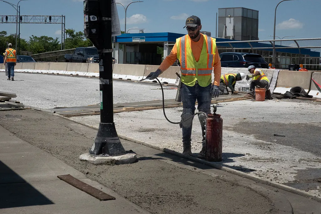 Construction worker wets concrete during 2025 heat wave