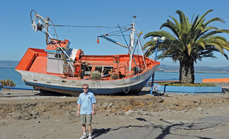 David Baska standing infront of the ship Dona Sofia on a beach after a Tsunami in Chile 2010